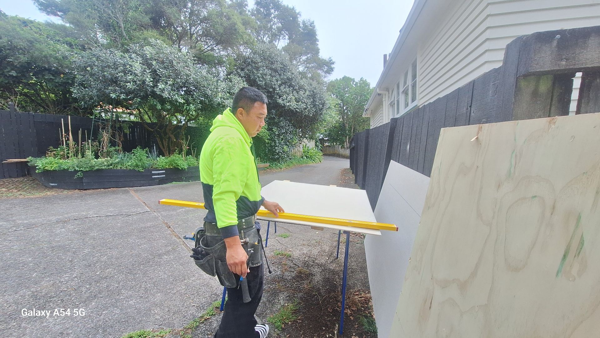 TradePlus carpenter checking a panel with a level on an Auckland job site